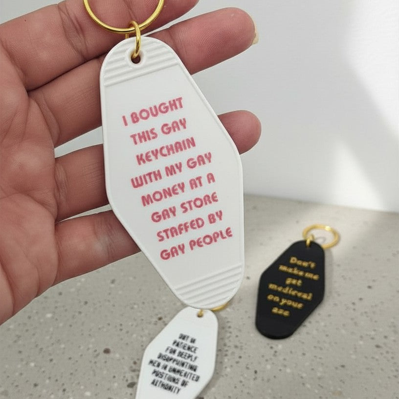 Keychain with text held by a hand on a concrete surface
