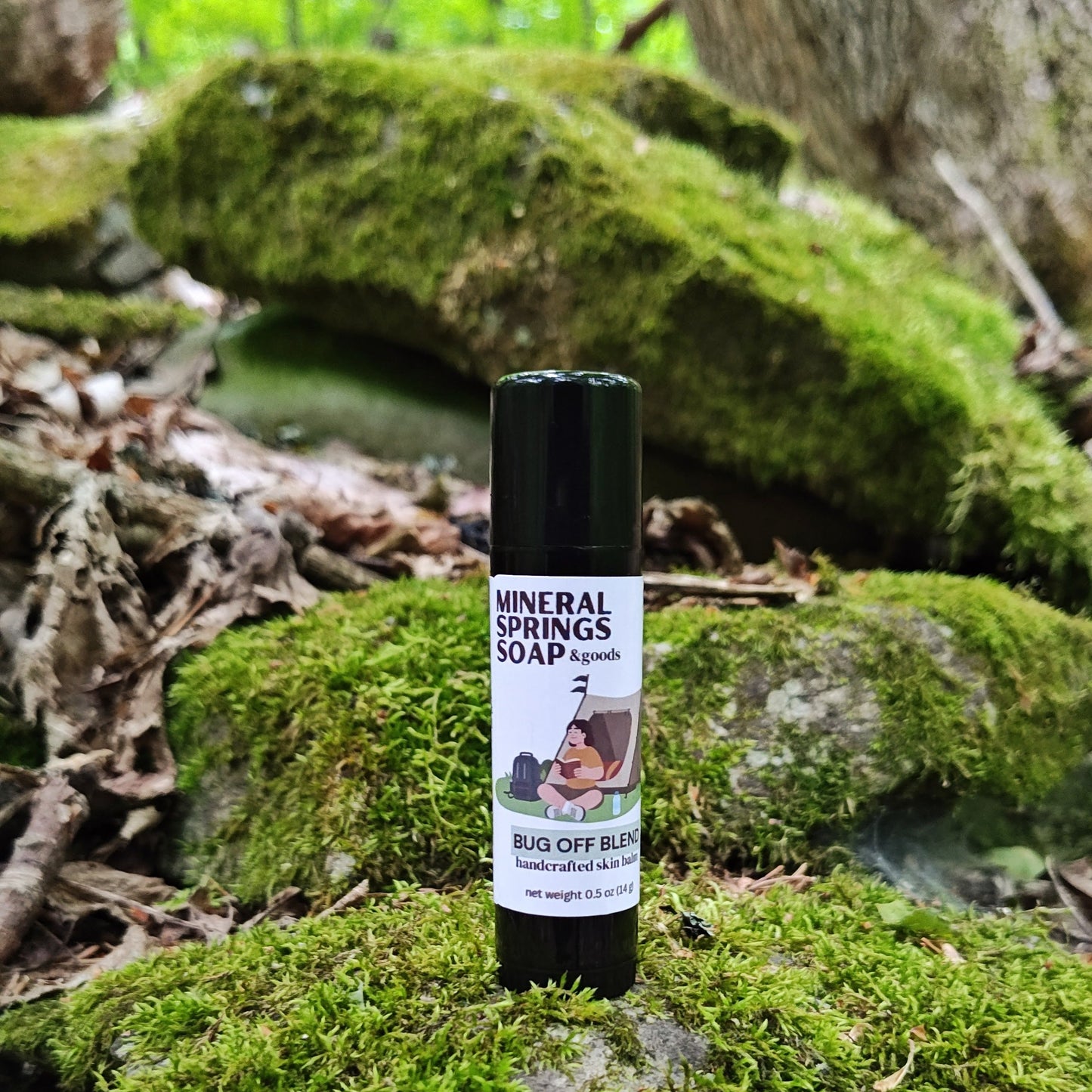 Tube of Mineral Springs Soap bug off skin balm on a mossy rock with a forest background
