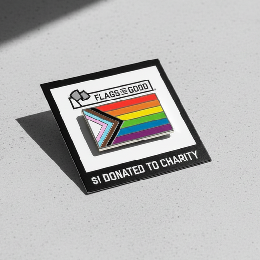 Pin with Progress Pride flag design on a gray concrete surface