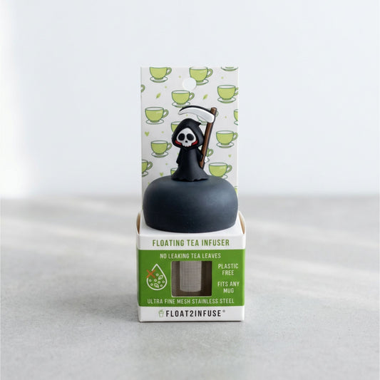 A floating tea infuser by Float2Infuse in its retail packaging, featuring a black spherical infuser topped with a grim reaper figure holding a scythe, set against a light gray background.