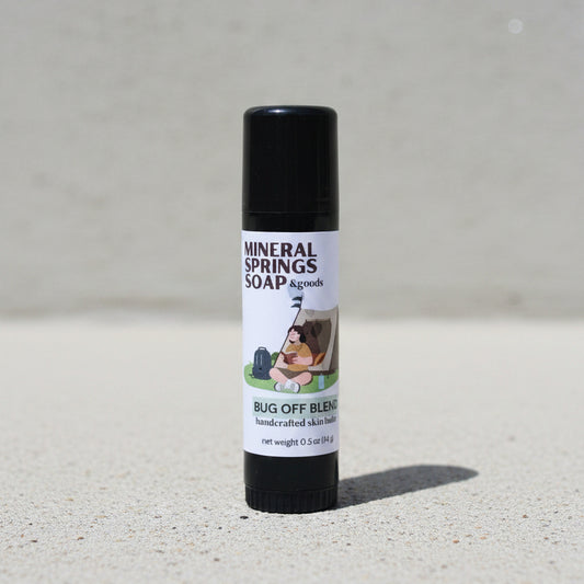 Roll-on stick of Mineral Springs Soap & Goods Bug Off Blend on a concrete photo backdrop surface