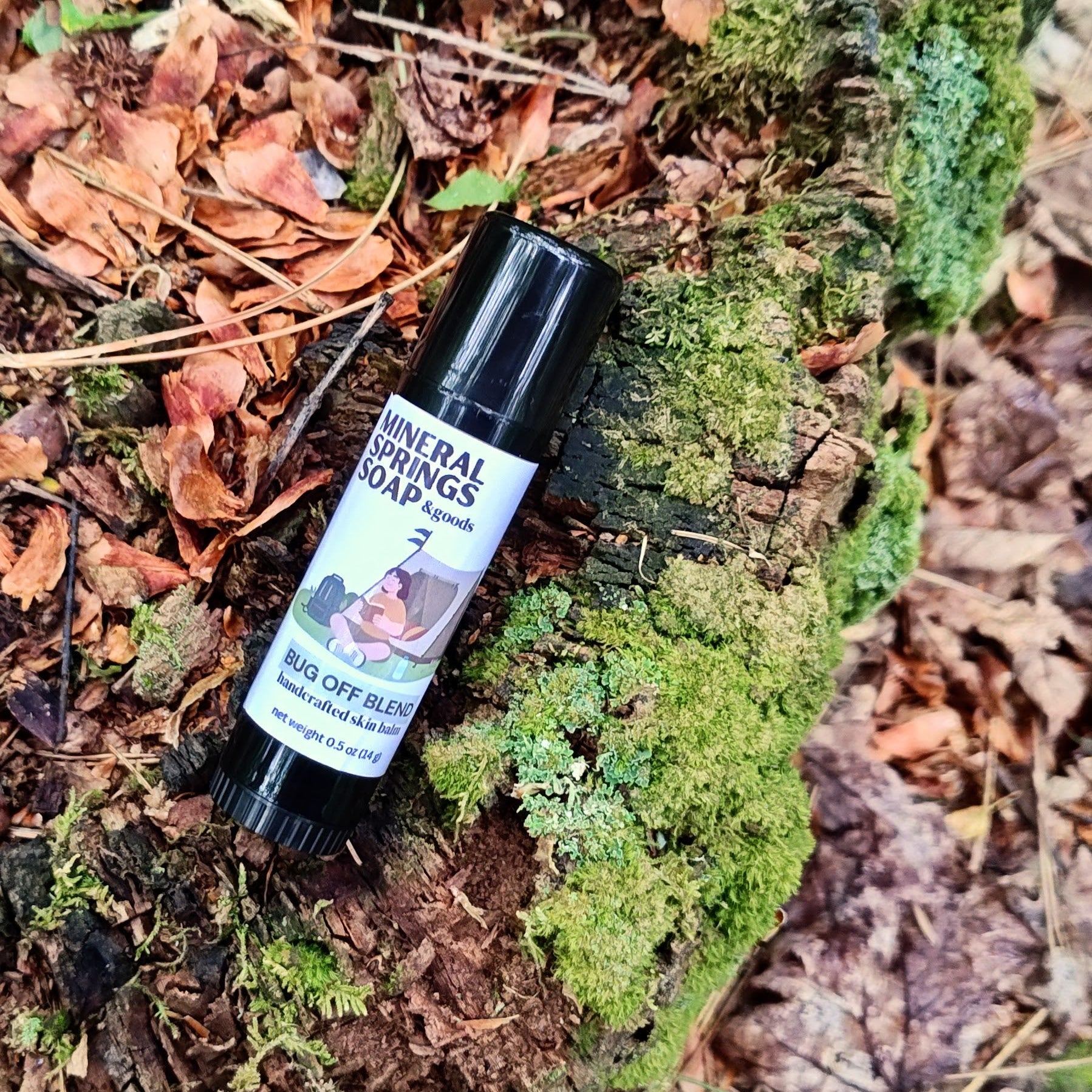 Roll-on bottle of bug repellent on a mossy forest floor